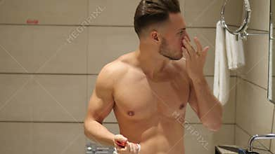 Handsome young man applying moisturizing cream