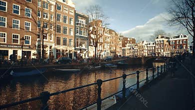 AMSTERDAM, NETHERLANDS - DECEMBER 26, 2017. People cycling along city canal embankment