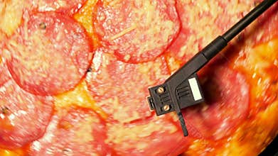 Italian pizza with salami as vinyl record rotating on turntable player. Pepperoni, concept of party with music and