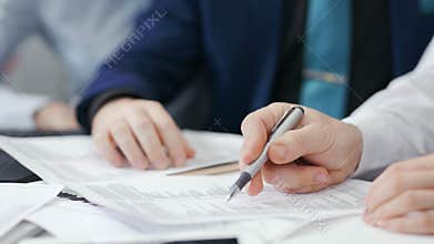 Close-up hands of two businessman during team meeting holding pen showing details at paper document