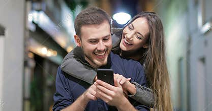 Couple joking watching phone content in the night