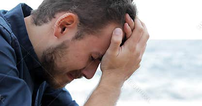 Sad man crying on the beach