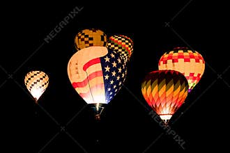 Colorful glowing hot air balloons flying at night against a black background of night sky