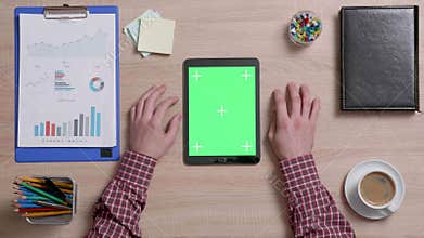 Top view of a man tap multiple times on the center of a green screen on tablet