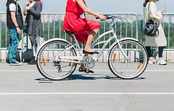 Lady on a bike. The girl in the red dress riding a bike around the city