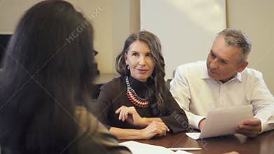 Mature couple buying house and talking to consultant in real estate agency.