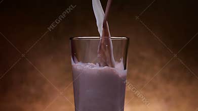 Chocolate milk and milk streams pour into glass, blending and mixing