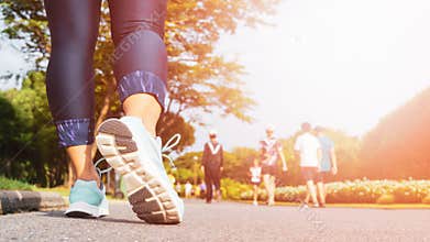 Young fitness woman legs walking with group of people exercise walking in the city public park in morning