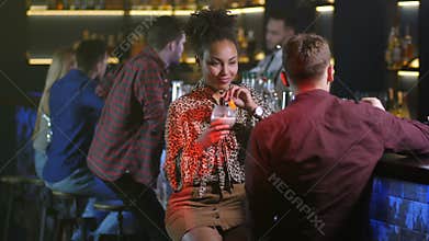 Dark-skinned female listening to man at nightclub