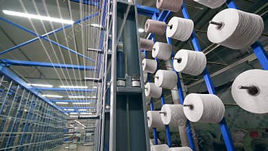 Automated machine spools thread onto big clews at a factory.