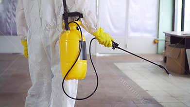 Exterminator in special clothes and in a protective mask sprays pesticide