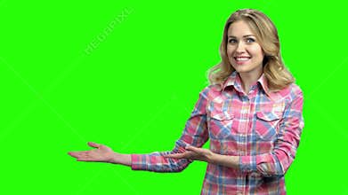 Happy surprised woman showing product on green screen.