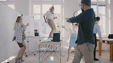 Young happy Caucasian company boss dancing together with with colleagues, fun team success celebration slow motion.