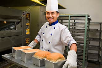 Baker holding fresh bread from oven