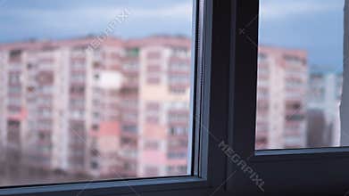 From Day to Night View through the Window at the Lights the Windows in High-rise Buildings