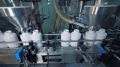 Working equipment filling bottles on a moving conveyor, automated line.