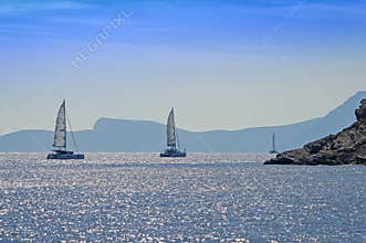 Rocky coast and sailing catamarans, Aegean sea