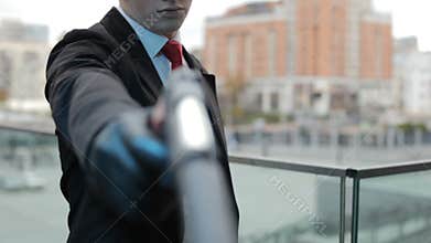 Hitman nervously taps the pistol on his arm.