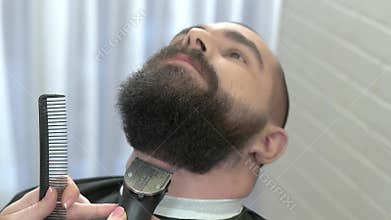 Beard trimming in barbershop.