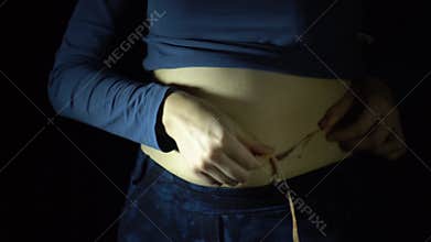 Female hands assess the waist in the presence of excess weight