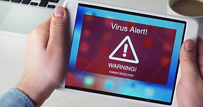 Man holds digital tablet with virus alert warning sign on the display