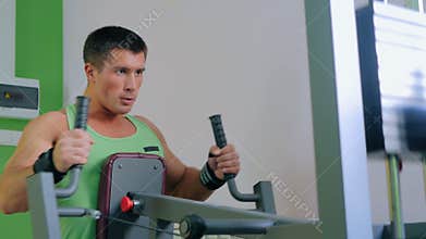 Athletic young man using exercise machine at gym