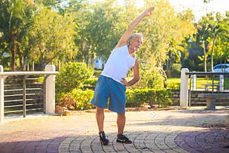 Grey Bearded Old Man in White Vest Bends Body in Park