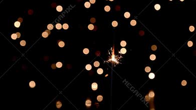 Sparkler burning in front of ambient lights
