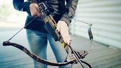 Girl inserts arrow into crossbow