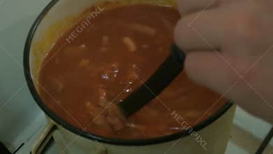 Male hands stir a ladle of the soup Solyanka. Russian cuisine.