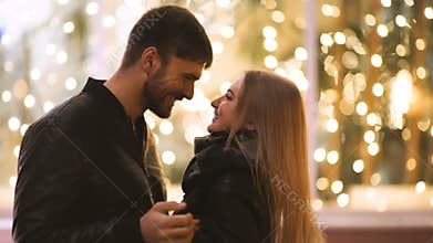 An attractive couple in love embrace and enjoy an intimate moment together, against the backdrop of city lights
