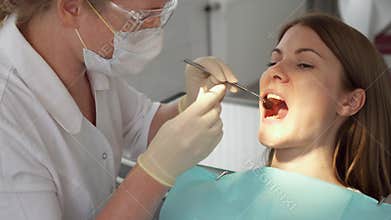 Dentist treating teeth to woman patient in clinic. Female professional doctor at work. Dental checkup