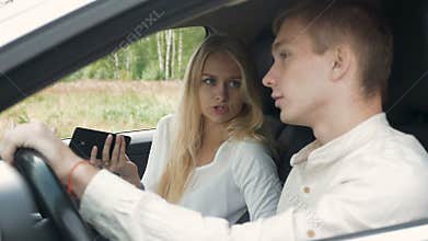 A blonde girl and her boyfriend are arguing, sitting in the car.