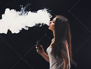 Young woman vaping e-cigarette with smoke on black