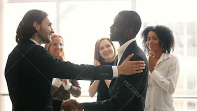 Boss promoting rewarding african american male employee, congratulating shaking hands