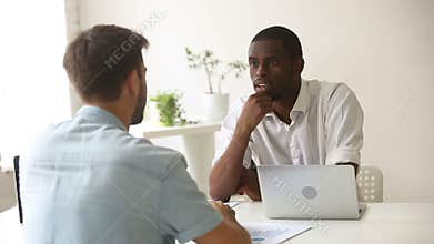 African and caucasian businessmen negotiating, discussing financial stats at meeting