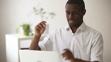 Happy african-american businessman feels relaxed finishing office work on laptop