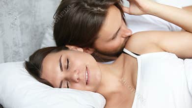 Affectionate husband wakening up sleeping wife by kissing, good morning