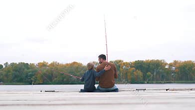 Father and son are fishing on pier