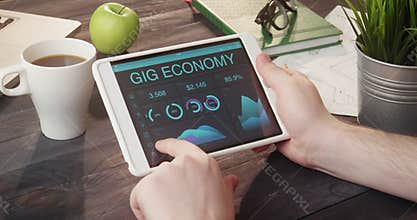 Looking at gig economy information using tablet computer at desk