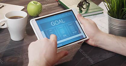 Reading about goal using tablet computer at desk