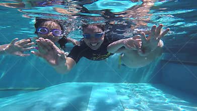 Father and children diving together in pool