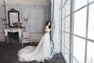 Beautiful bride, young model brunette woman, in stylish wedding dress with naked shoulders, with bouquet of flowers in