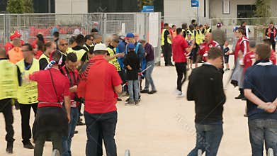 Stadium stewards standing in front of gate before game, spectators moving around