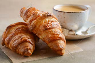 Cup of fresh coffee with croissant on concrete background