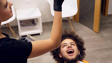 Footage of a dentists assistant checking a young mans shade of tooth color