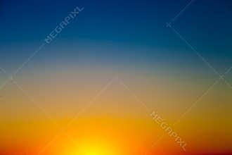 Background with gradient sunset sky in tones of yellow, orange and blue