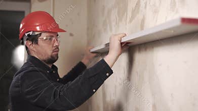 Builder is checking level of walls in repairing flat indoors