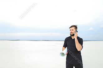 Topographer speaking on smartphone in deserted place holding w