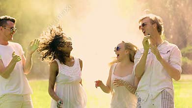 Happy young dancing friends spraying powder paint at music festival, Holi